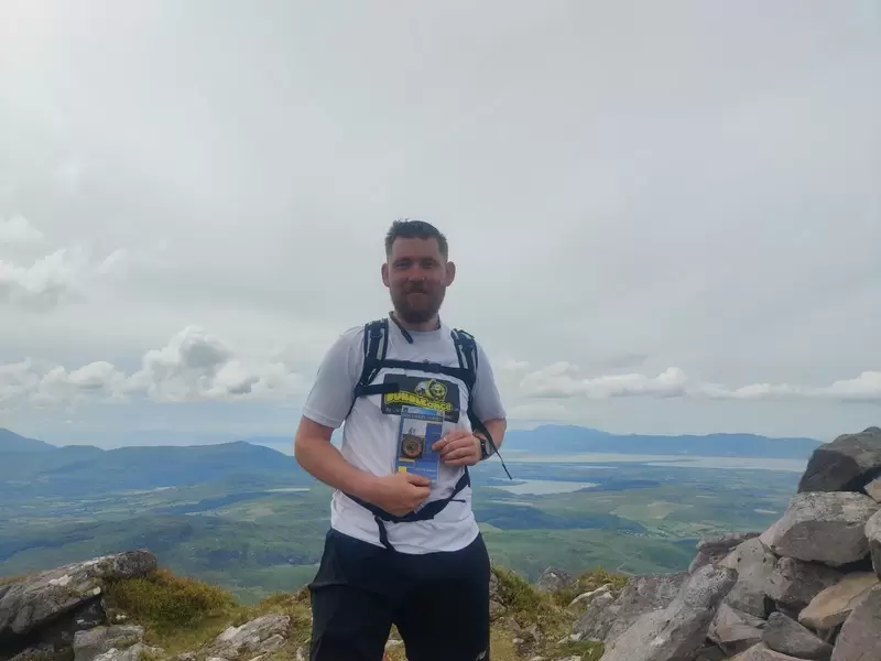 Vinny with a map and compass on top of Cnoc Íochtair