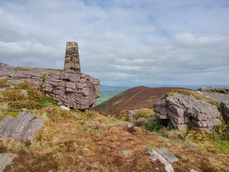 Seefin Trig Pillar on the rocky outcrop and more rock nearby. 