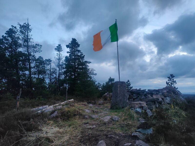 Trig pillar of Knocknaskagh with flag pole with Irish Flag erected on trig.