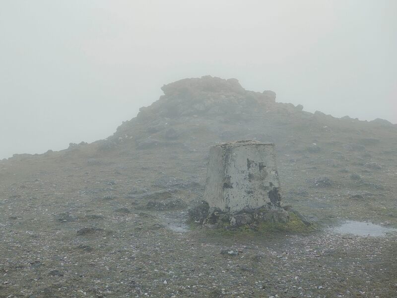 broken Trig pillar of Galtymore with cairn of stones in background