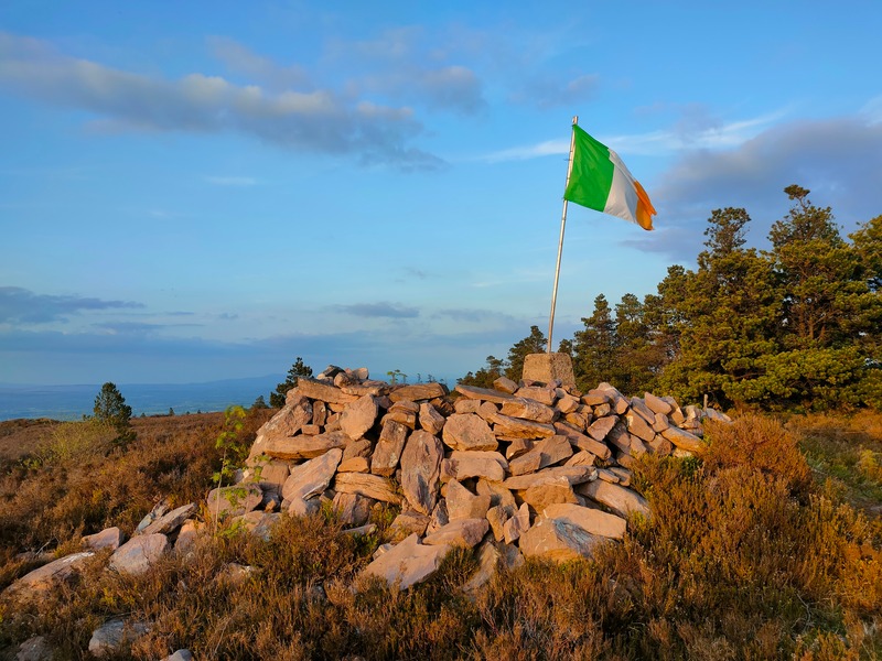 Ireland flag on Knocknaskagh Trig pillar surrounded by pile of rocks