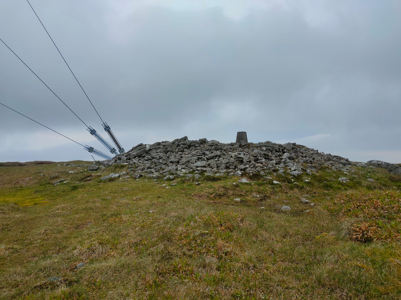 Cairn of stones and Trig Pillar of Mount Leinster. Three steel rope ties of the mast also visible.