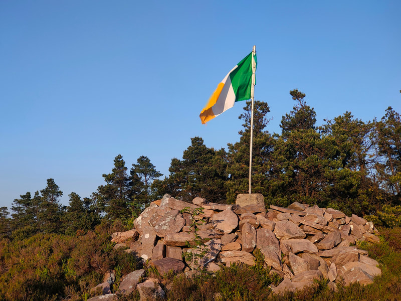 Irish Flag mounted to Trig Pillar of Knocknaskagh among a mound of stones