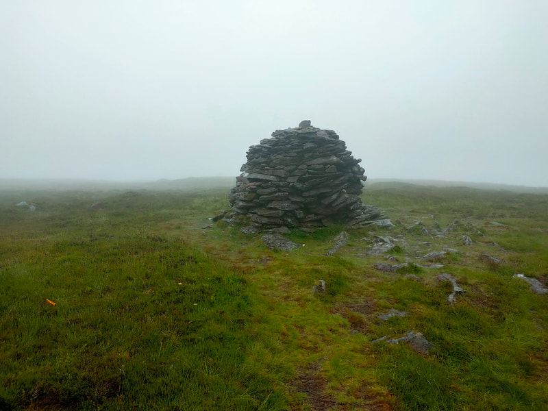 Large mound of stones marking the top of Musheramore, low cloud in background