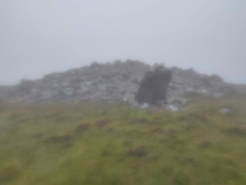 Cairn of stones and large standing stone of Knocknafallia East in mist