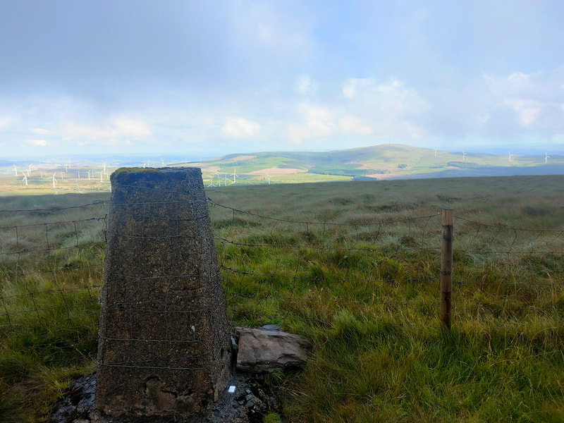 Caherbarnagh Trig Pillar with fence on each side and Mullaghanish across the valley