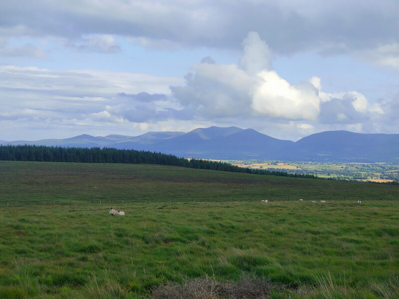 Knockmealdowns against a cloudy sky, green surface of lower Galty mountains in foreground