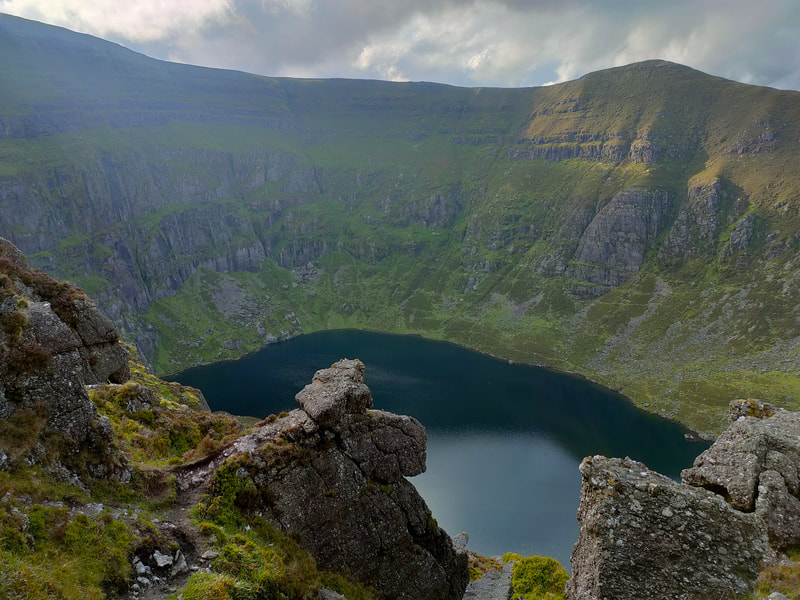 Dark water of Coumshingaun Lake surrounded by the steep mountain sides