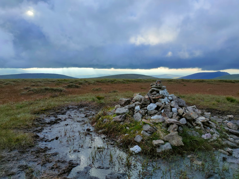 Surface water at a wet Kilclooney Mountain top. Pile of stones in the centre.