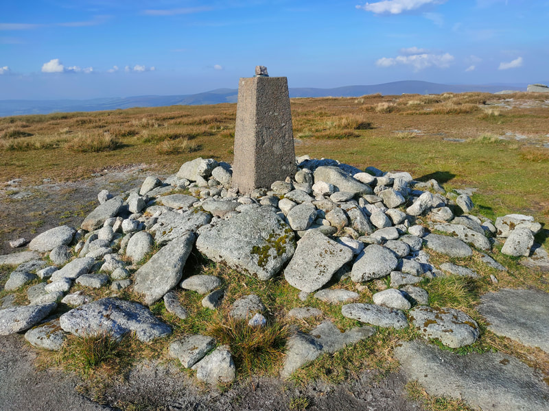 Trig Pillar of Mullaghcleevaun surrounded by stones.