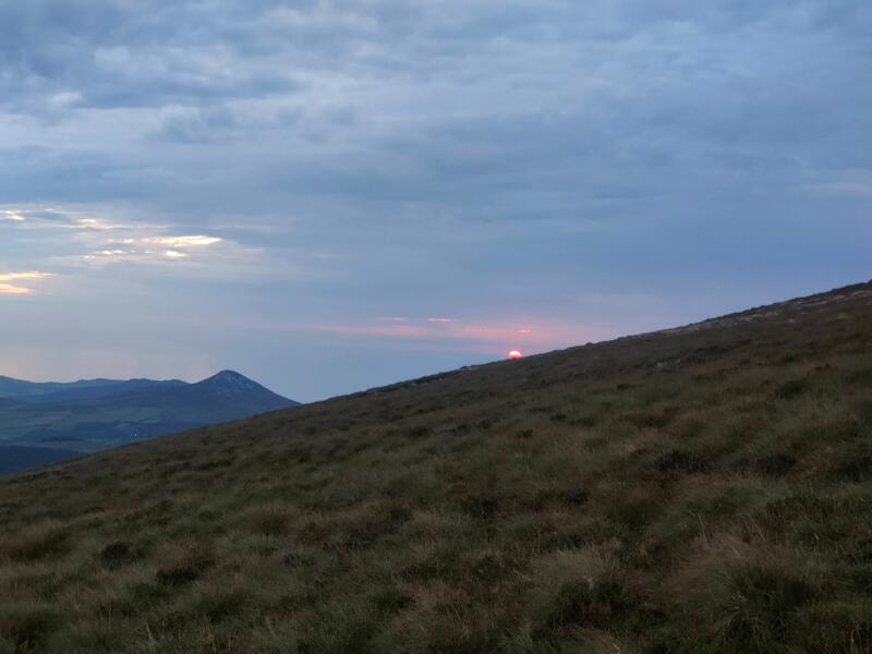 Sun rising from grassy mountain top