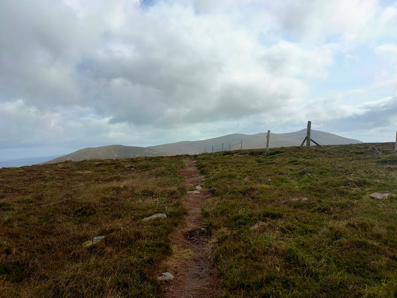 A worn mountain path withthe Knockmealdown range of mountains against the skyline.
