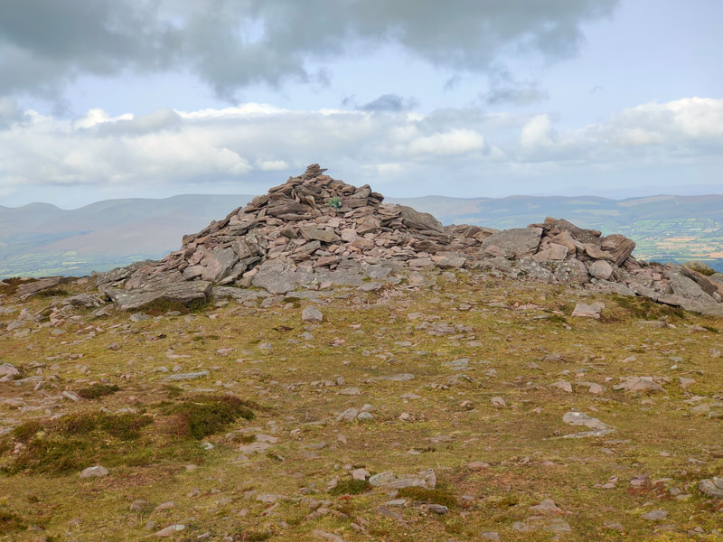 Mound of stones marking the top of Sugarloaf Hill with the Galty mountains on the horizon