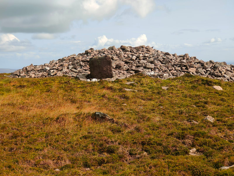 Large stone in front of a cairn of stones on mountain