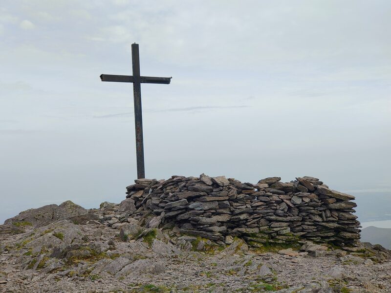 Top of Carrauntoohil Cairn of stones and Steel Cross, white skybackground