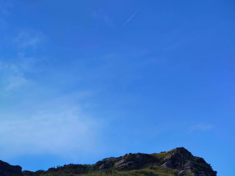Airplane in bright blue sky above mountain top