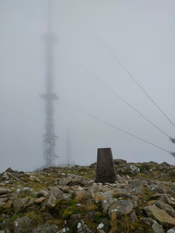 Trig Pillar with telecommunication mast in the background lost in cloud
