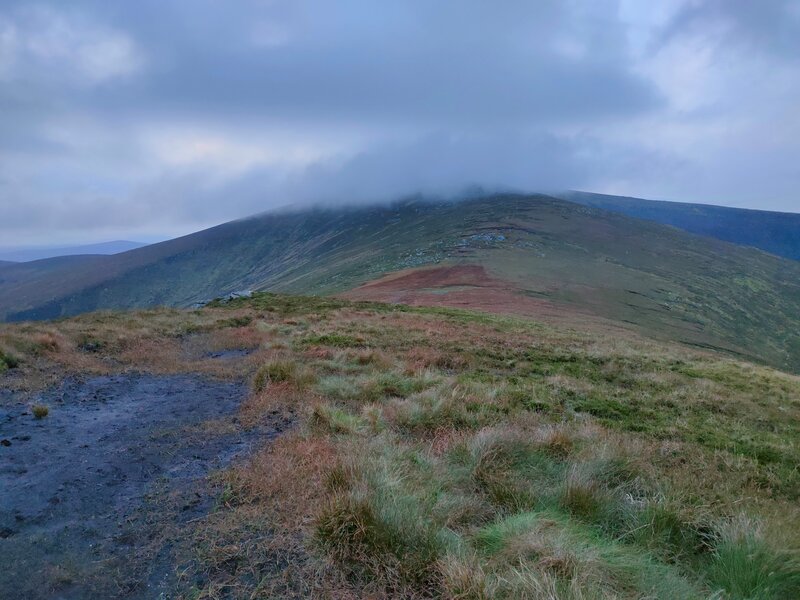 Muddy mountain path with peak lost in cloud