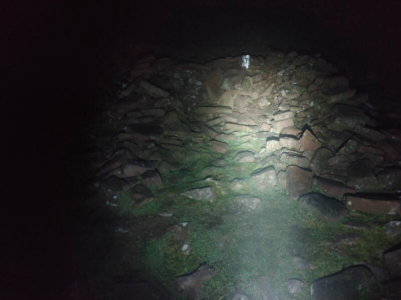The silver box containing the log book lit by the head torch on Temple Hill 