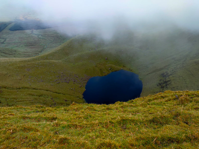Dark blue lake surrounded by grassy mountain slopes